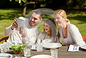 Happy family with tablet pc at table in garden