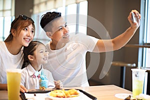 Happy family taking selfie in restaurant.