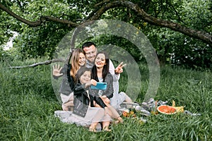 Happy family taking selfie on smartphone during picnic time