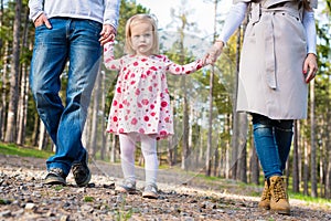 Happy family taking a walk in a park, family holding hands walking together along forrest path