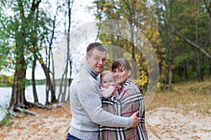 Happy family with their baby daughter spending time outdoor in the autumn park