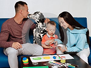 Happy family with their son and dog Dalmatian sit at the table at home