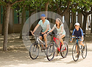 Happy family of three cycling on street road
