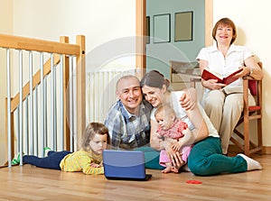 Happy family of three generations using blue laptop in home int