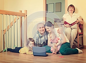 Happy family of three generations using blue laptop in home int