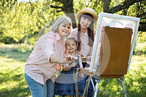 Happy family three generations of women. Family painting outdoors. Cute little girl having fun with her mom and grandma