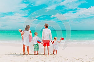 Happy family with three kids walk on beach