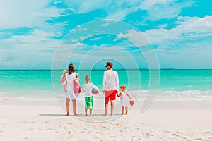 Happy family with three kids walk on beach