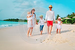 Happy family with three kids walk on beach