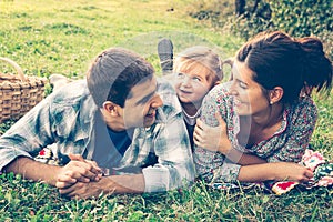 Happy family of three lying in the grass in autumn