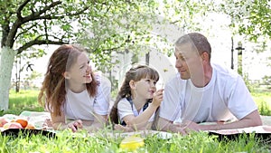 A happy family of three people at a picnic.