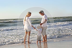 Happy Family of Three People Playing in Ocean While Walking Along Beach