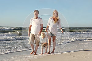 Happy Family of Three People Walking on Beach Along Ocean