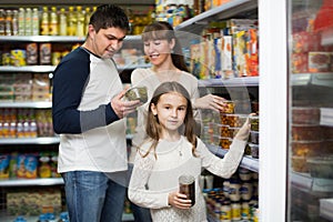 Happy family of three purchasing canned food