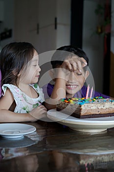 Happy family with two sibling decorating birthday cake at home.