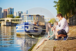 Happy family of three sitting on the bank of the Seine