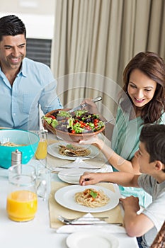 Happy family of three sitting at dining table