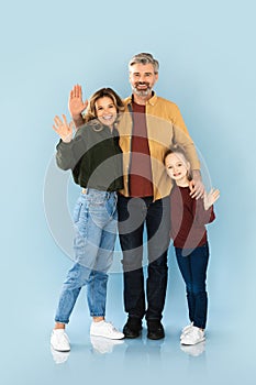 Happy Family Of Three Waving Hands Standing Over Blue Background