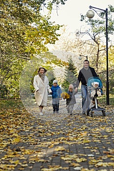 Happy family with three young children in an autumn park on a sunny day. The golden time of the year for walks and outdoor