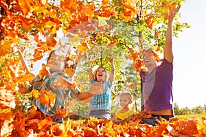 Happy family throwing leaves in air while sitting