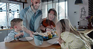 Happy family time concept, young father brings in holiday muffins to celebrate with mother and cute children slow motion