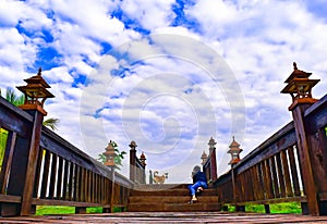 Happy family time, a woman is taking a photo of her dog on the wooden bridge with beautiful white cloudy sky.