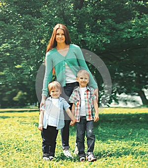 Happy family together! Mother and two children sons walking in the park on summer day