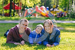 Happy family together in outdoor park at spring sunny day. Mom, dad and son in the garden. Group of people on green