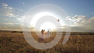 A happy family, together in the park at sunset on a sunny day, launch a kite plane into the sky. Silhouette mom, dad