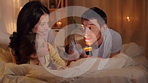 Happy family with torch light in bed at home