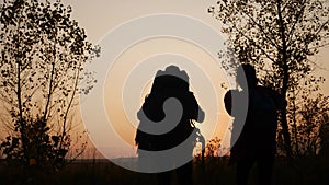 happy family tourists go hiking in the park sunset silhouette. adventure travel concept. teamwork. happy family a