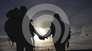 Happy family tourists walking holding hand silhouette at sunset. Hikers teamwork travel concept. Man and woman couple