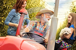 Happy family on tractor in orchard