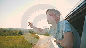 A happy family travels by car. A carefree teenager looks out of a car window, a boy waves, a child enjoys the landscape