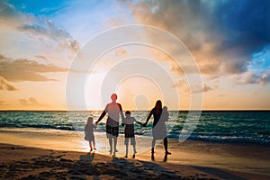 Happy family with tree kids walk at sunset beach