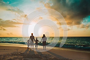 Happy family with tree kids walk at sunset beach