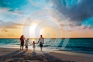 Happy family with tree kids walk at sunset beach