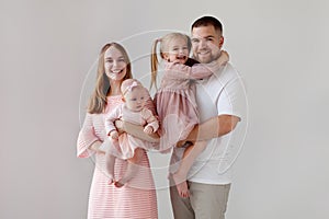 Happy family with two child on isolated white background. Smiling Parents with children girls in their arms wearing