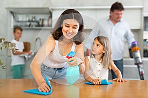 Happy family with two children doing cleaning in kitchen