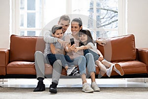 Happy family with two children having good time using smartphone.