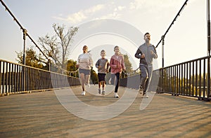 Happy Family With Two Children Jogging In The City Park At Sunset