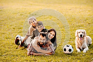 Happy family with two children lying in a pile on grass with dog sitting