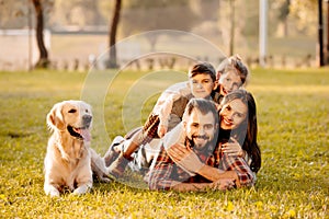 Familia feliz dos acostada en sobre el césped el perro 