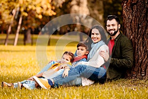 Happy family with two children sitting together on grass