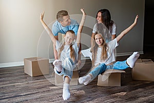 Happy family with two daughters have fun in their new home. Parent with kids enjoy their moving day