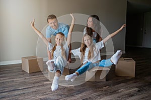 Happy family with two daughters have fun in their new home. Parent with kids enjoy their moving day