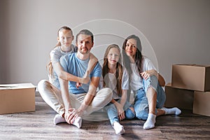 Happy family with two daughters have fun in their new home. Parent with kids enjoy their moving day