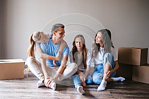 Happy family with two daughters have fun in their new home. Parent with kids enjoy their moving day