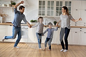 Happy family with two kids dancing in modern kitchen together