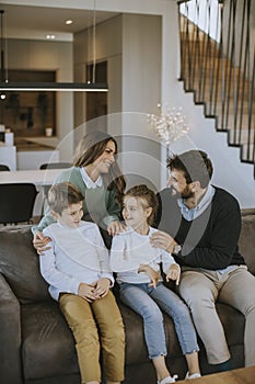 Happy family with two kids enjoy time together on couch in living room